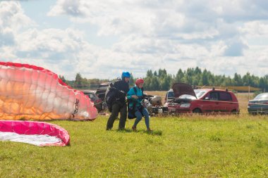 Tver, Rusya - 9 Ağustos 2020: Tandem Paragliding pistten kalkış. İnsanlar etrafta neler yapıyor. Arka planda bulutlu mavi gökyüzü görünür..