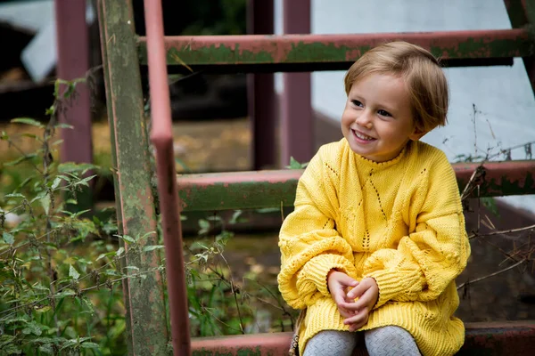 Beautiful happy girl with a short haircut in a yellow knitted sweater is.sitting on the stairs, Autumn Portrait. Welcome warm autumn. Golden autumn concept, Indian summer, September.