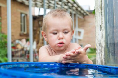 Bir çocuk ellerini su varilinde yıkıyor..