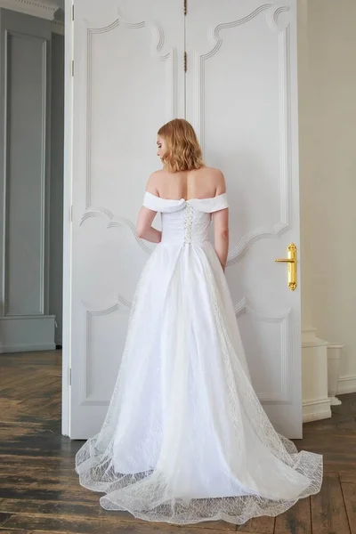 The bride stands with her back to the camera showing off a beautiful wedding dress from the back