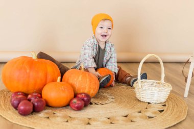 A little boy sits among pumpkins with a basket of ducklings. clipart