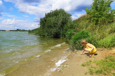 Sarı tulumlu küçük bir kız kıçının üstüne oturur ve oynar.