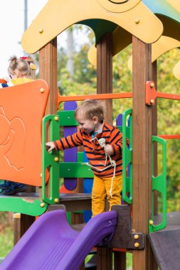 Mutlu Cadılar Bayramı. İskelet oyuncağı elinde komik bir çocuk oyun parkında kayıyor.