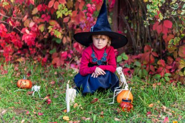 Cadılar bayramında bahçede poz veren cadı kostümlü küçük kız..
