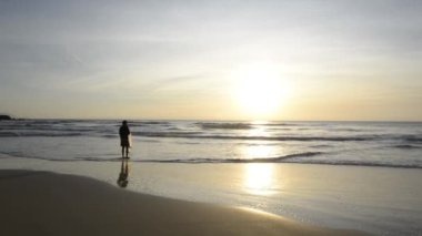 Sırtında ağla kıyıda balık bekleyen balıkçıların arka görüntüsü. Güneşin doğuşundaki sahili, arka plandaki adayı. Brezilya 'da tekir balıkçılığı dönemi