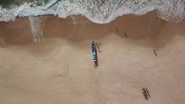 海岸に係留された木製の漁船のズームのトップビュー 空中展望 人々は砂浜を歩いている 波の動き — ストック動画