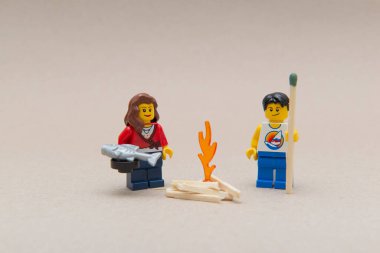 Florianopolis - Brezilya, 14 Haziran 2020: Ateşin yanında kamp yapan ve ısınan birkaç minyatür figür. Elinde kocaman bir kibrit çöpü tutan adam. Seçici odaklanma. Küçük rakamlar Lego Grubu tarafından üretiliyor..