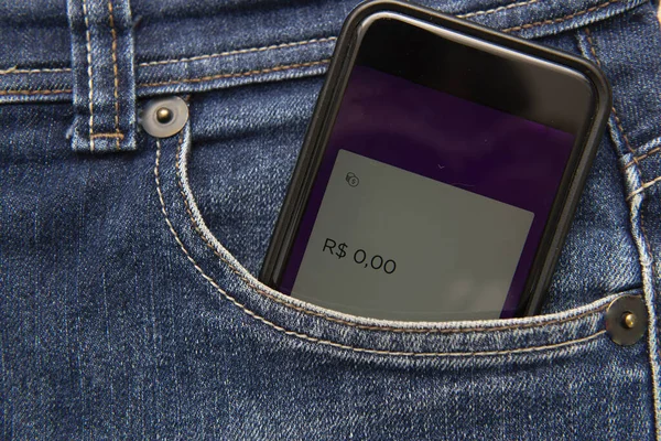 Close up of cellphone in pants pocket showing screen with zero money balance. Concept of being economically broken. Virtual money in your pocket.