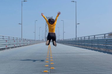 Çelik köprünün arka planında atlayan kısa saçlı kadının arka planı