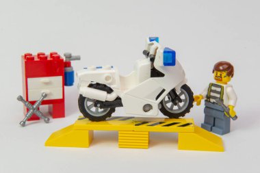 Florianopolis, Brezilya. 19 Eylül 2020: Yağ lekeli tamirci mini figür beyaz arka planda bir motosikleti tamir ediyor. Tamire ihtiyacı olan bir motosiklet. Uzayı kopyala Seçici odak.