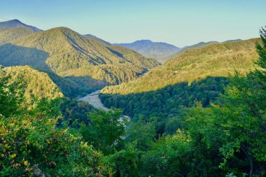 The Shakhe river among the mountains covered with forests, in the Lazarevsky district of Greater Sochi, at sunset clipart