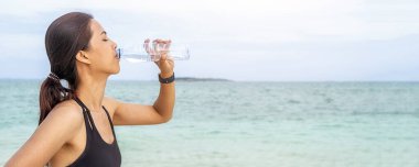 Tropikal sahilde su içen Asyalı kadın, Yaz Sahil Tatili Konsepti.