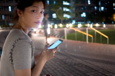 Şehirde cep telefonu kullanan genç bir kadın.