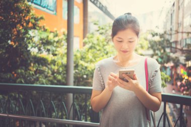 Şehirde cep telefonu kullanan genç bir kadın.