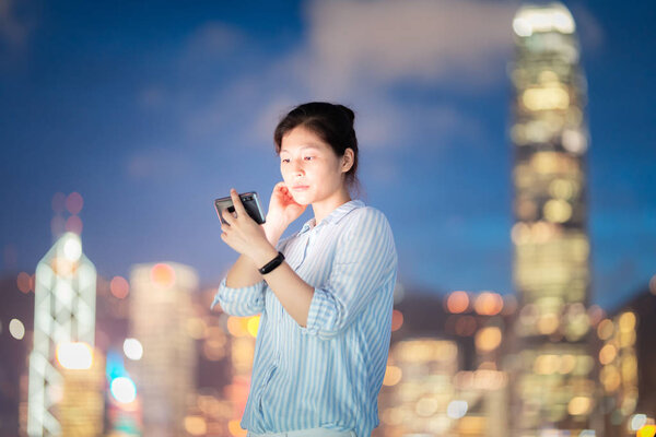 Young woman using smarphone in Hong Kong city street at night