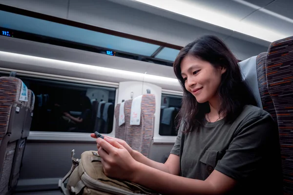 asian woman traveling by train and using gadget