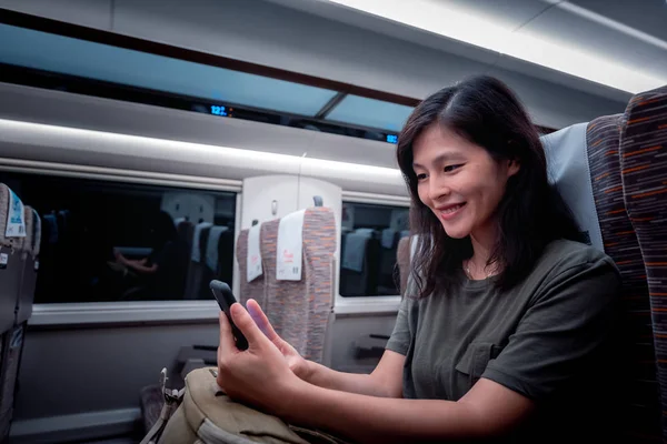 asian woman traveling by train and using gadget