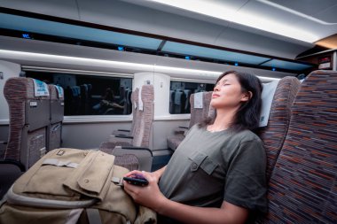 Asyalı kadın tren ile seyahat ve gadget'ı kullanma 