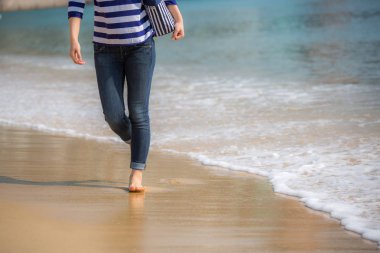 Sahilde kumların üzerinden yürüyen kadın 