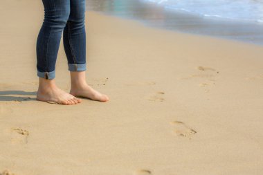 Sahilde kumların üzerinden yürüyen kadın 