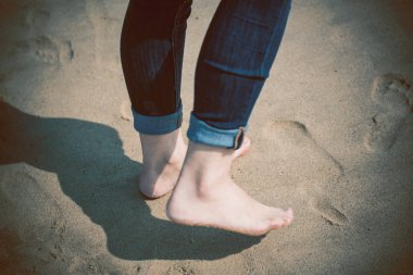 Sahilde kumların üzerinden yürüyen kadın 