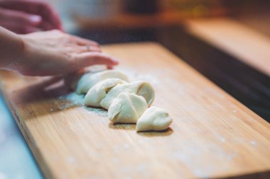 Kadın hamur köftesi derisi hazırlar, ahşap masada hamur yapar.