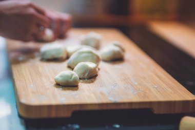 Kadın hamur köftesi derisi hazırlar, ahşap masada hamur yapar.
