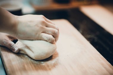 Kadın hamur köftesi derisi hazırlar, ahşap masada hamur yapar.