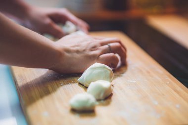 Kadın hamur köftesi derisi hazırlar, ahşap masada hamur yapar.