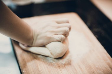 Kadın hamur köftesi derisi hazırlar, ahşap masada hamur yapar.