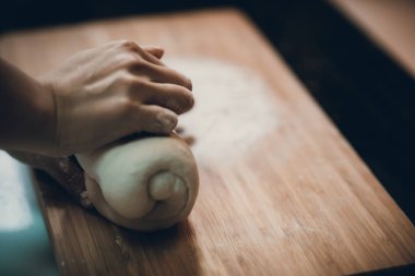 Kadın hamur köftesi derisi hazırlar, ahşap masada hamur yapar.