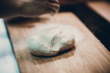 Kadın hamur köftesi derisi hazırlar, ahşap masada hamur yapar.
