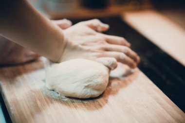 Kadın hamur köftesi derisi hazırlar, ahşap masada hamur yapar.