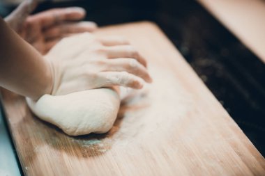 Kadın hamur köftesi derisi hazırlar, ahşap masada hamur yapar.