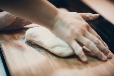 Kadın hamur köftesi derisi hazırlar, ahşap masada hamur yapar.