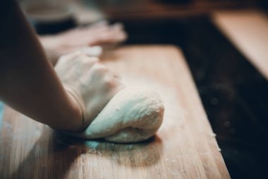 Kadın hamur köftesi derisi hazırlar, ahşap masada hamur yapar.