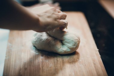 Kadın hamur köftesi derisi hazırlar, ahşap masada hamur yapar.