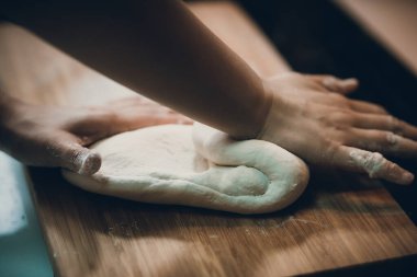 Kadın hamur köftesi derisi hazırlar, ahşap masada hamur yapar.