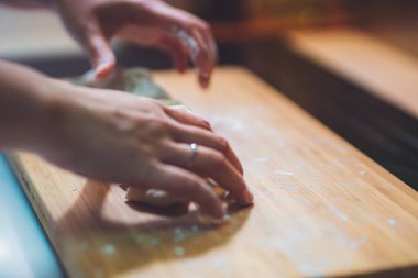 Kadın hamur köftesi derisi hazırlar, ahşap masada hamur yapar.