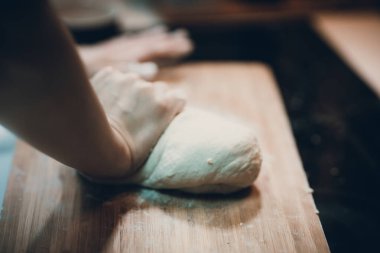 Kadın hamur köftesi derisi hazırlar, ahşap masada hamur yapar.