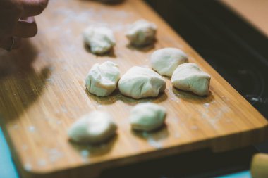 Kadın hamur köftesi derisi hazırlar, ahşap masada hamur yapar.