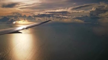 Gün batımında deniz üzerinde uçan uçak kanadı