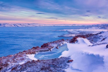 Donmuş bir göl ve kışın gün batımında Barents Denizi kıyısında. Teriberka, Murmansk Bölgesi, Kola Yarımadası. Rusya