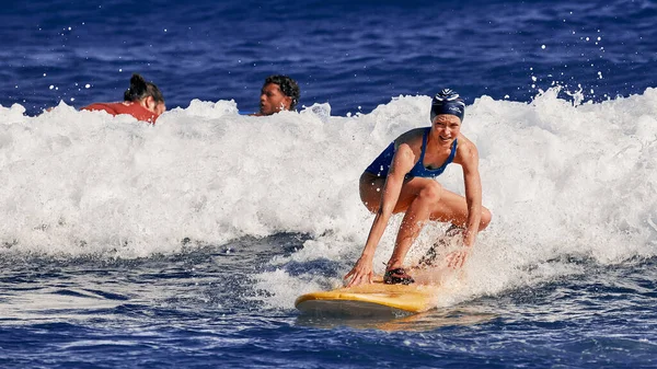 美しい若い女性がサーフボードの上に立つことを学んでいます。サーフスクール。水スポーツ,大西洋ドミニカ共和国.2016年12月29日 — ストック写真