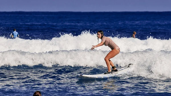 美しい若い女性がサーフボードの上に立つことを学んでいます。サーフスクール。水スポーツ,大西洋ドミニカ共和国.2016年12月29日 — ストック写真