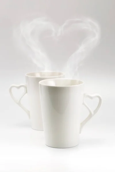 Un par de taza blanca con vapor de corazón y mango del corazón — Foto de Stock