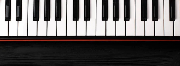 synthesizer keyboard on black wooden background with empty space for text.