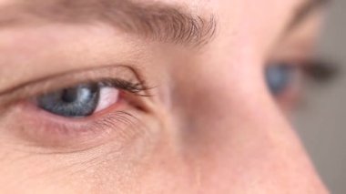 Gray-blue pupil of a young girl moves left, right, watching some movement or reading
