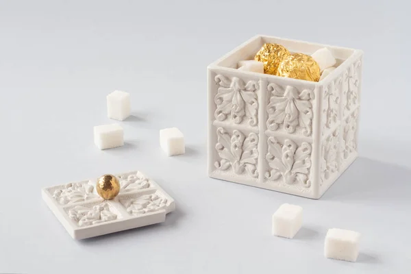 İçinde küp şeker ve altın şekerler olan beyaz şeker kasesi. Tatlı, tatlı, şekerler kavramsal imaj. Lüks, çay partisi, tatlılar