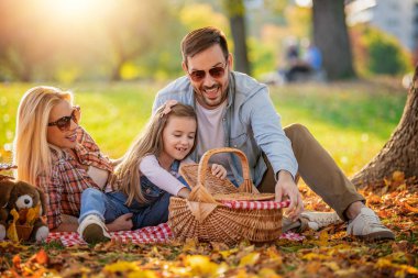 Mutlu aile parkta piknik yapıyor. Üç çocuklu mutlu aile birlikte eğleniyor. Aile eğlencesi dışarıda..
